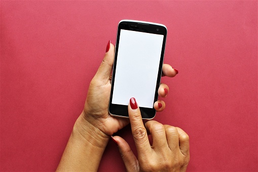 women hands holding smartphone put index finger red nail polish on the phone photo isolate on pink