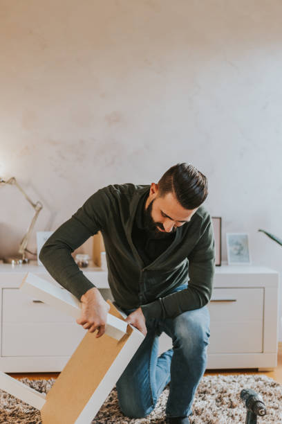 istock Man is assembling table legs in his new living room 1203774982
