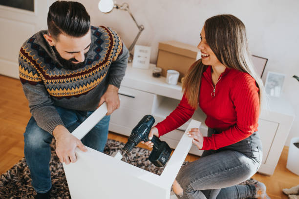 istock Young woman is using a drill to assemble table with her boyfriend 1203775635