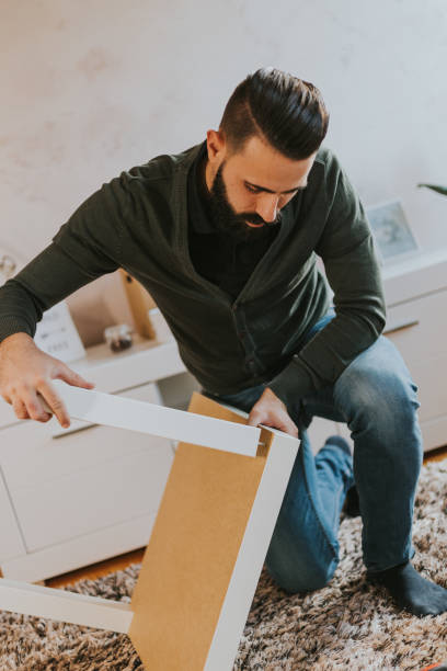 istock Man is assembling table legs in his new living room 1203775653