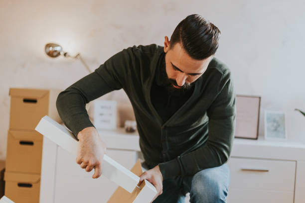 istock Man is assembling table legs in his new living room 1203775662