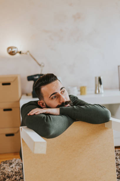 istock Man is taking a break from assembling furniture is his new home 1203775673