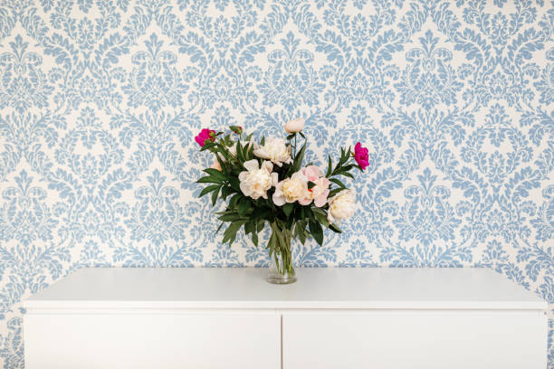 istock Peonies Fresh Cut Flowers in vase with copy space on white table on blue background 1203777563