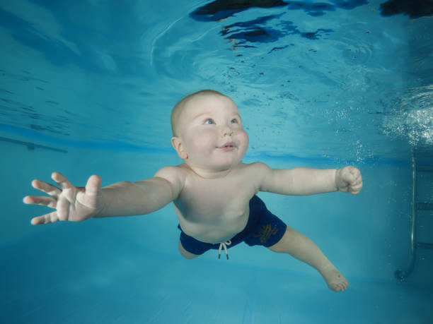 istock Little boy learns to dive underwater in a swimming pool