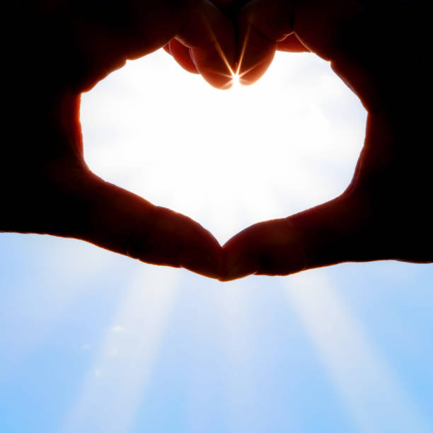 istock Hands forming a heart shape over the sun 1203779131
