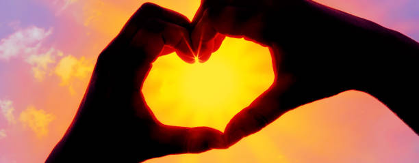 istock Hands forming a heart shape over the sun 1203779156
