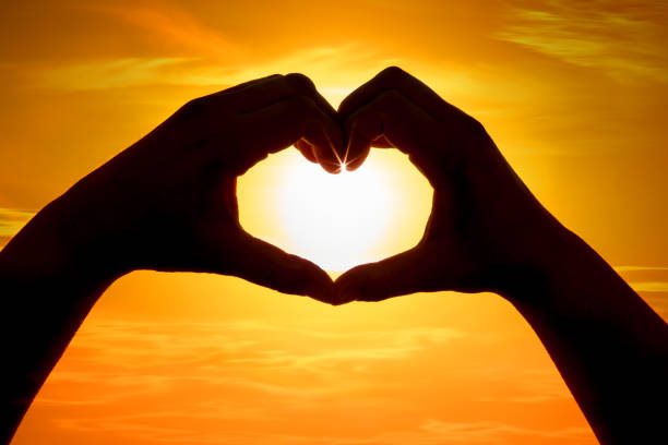 istock Hands forming a heart shape over the sun 1203779229