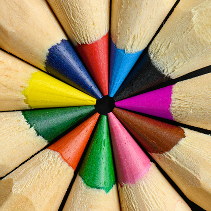 Colored wooden ordinary pencils in a circle closeup background.