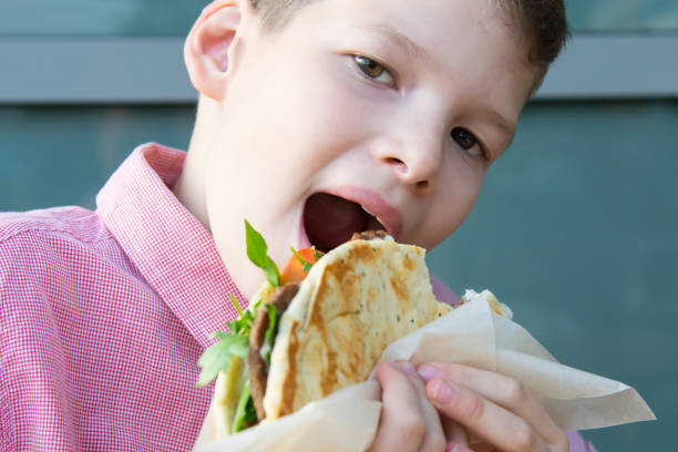 A boy peering into a paper bag with cakes from a cafe, ideal for bakery promotions,cafe advertisements, food blogs, dessert-themed social media, event invitations, or lifestyle marketing content.