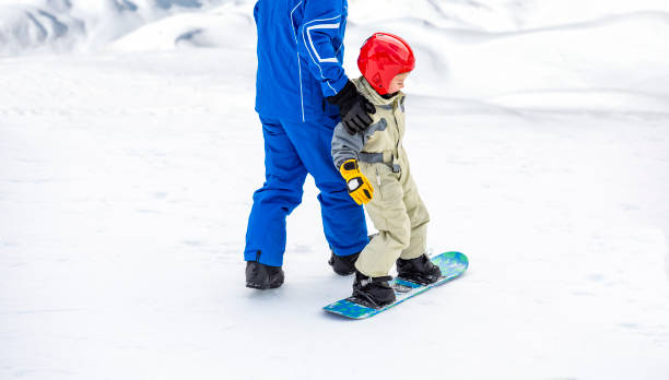 istock Child on the slopes for the first time on a snowboard 1203781629