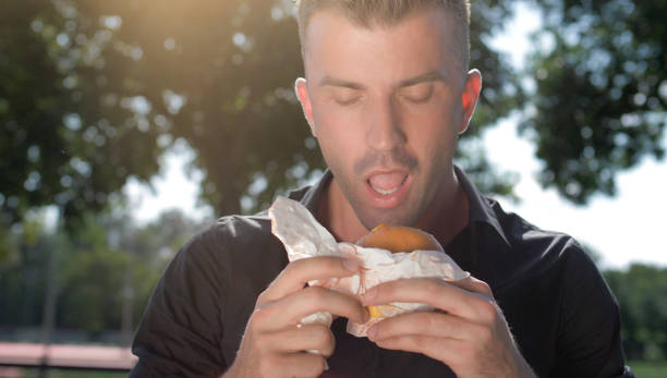 istock Guy eating burger on the street 1203781677