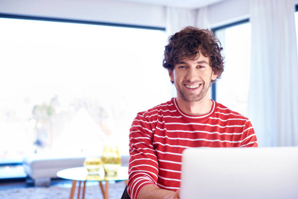 istock Happy young man with notebook sitting at desk at home 1203783180