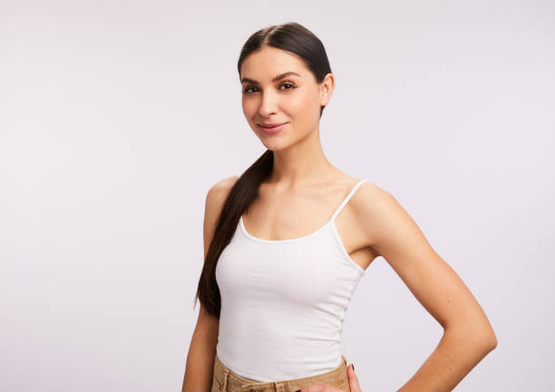 istock Young woman smiling while standing against a gray background 1203784977
