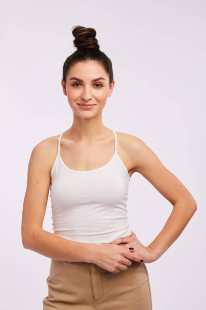 istock Smiling woman standing on gray with her hand on her hip 1203785648