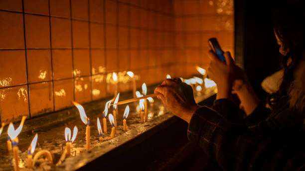 istock woman lighting candles in church 1203786122