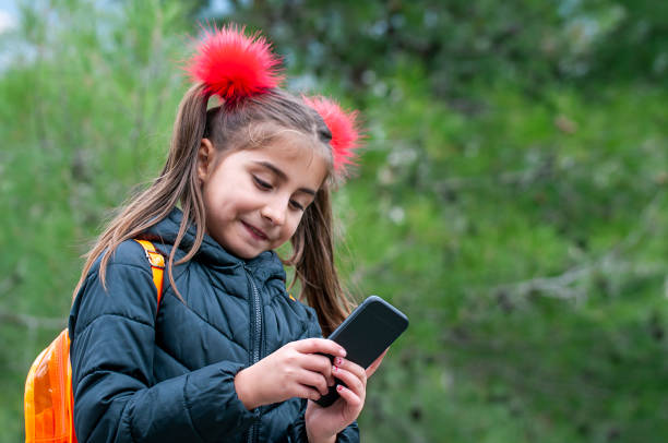 istock Littel girl using mobile phone by garden 1203786562