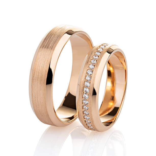Pair of rose gold wedding rings with diamonds and matte surface isolated on white stock photo