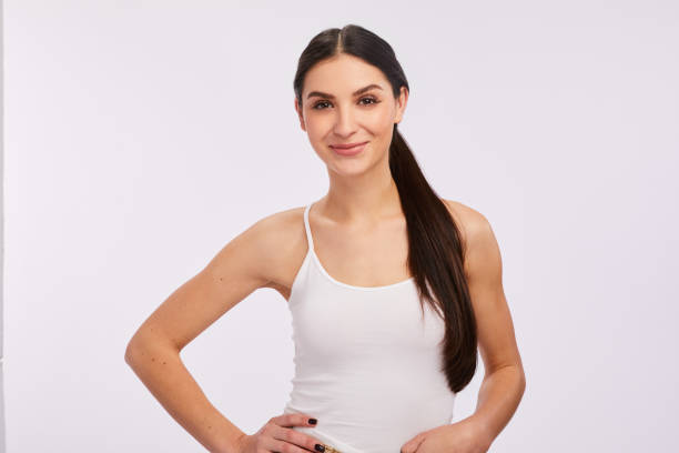 Smiling young woman standing confidently against a gray background