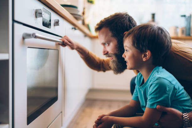 Father and son cooking dinner at home Single father with son baking at home and looking through the oven glass home cooking stock pictures, royalty-free photos & images