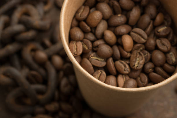 istock Coffee beans in a paper cup close-up. 1203795254