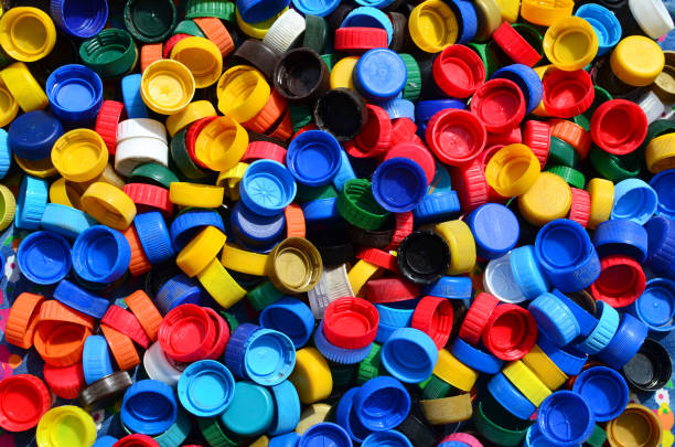 istock Plastic bottle caps background. Cap material is recyclable.Remove lids from plastic bottles before recycling them. Recycling collection and processing plastic bottle caps 1203795739