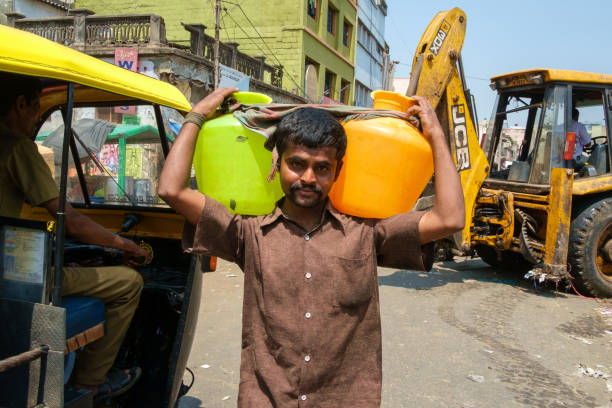 Bengaluru, India - April 25, 2016: Worker carries large jugs at K.R. Market, Bengaluru’s largest wholesale market.