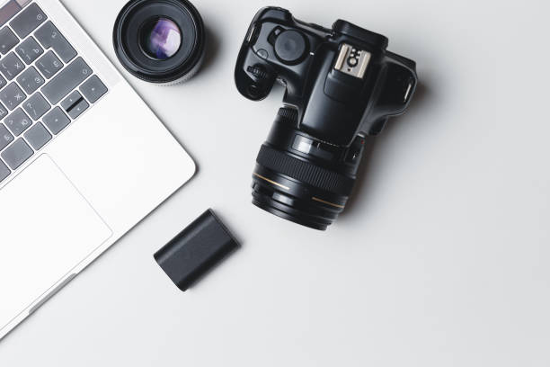 istock Photographer's workplace on a white background. Modern laptop, digital camera, lens, battery, smartphone. Minimalism. Top view. Copy space. Equipment for the photographer. The concept of freelancing 1203798748