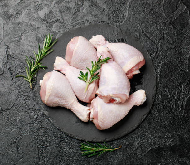 Raw uncooked chicken legs with spices and ingredients for cooking on cutting board