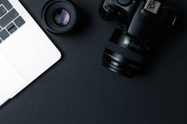 istock Photographer's workplace on a dark background. Modern laptop, digital camera, lens, battery, smartphone. Minimalism. Top view. Copy space. Equipment for the photographer. The concept of freelancing 1203801326