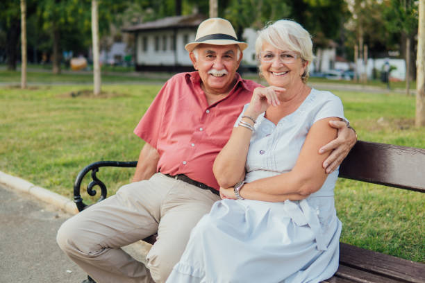 istock Elderly couple sitting in a public park 1203801980