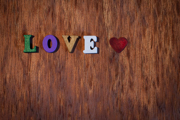Inscription love and wooden heart on the background. - fotografia de stock