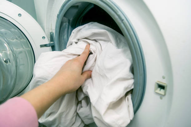 istock Woman hands loading linen into washing machine stock photo 1203803653