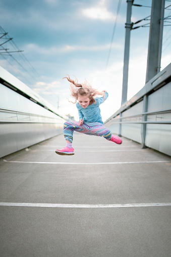 Austria, Salzburg. little girl is dancing on a modern bridge in salzburg.