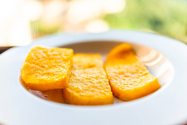 Polenta yellow orange corn cakes slices fried on white plate in restaurant appetizer golden color with blurry background