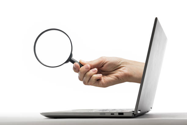 istock The laptop with magnifier in human hand on white. 1203809438