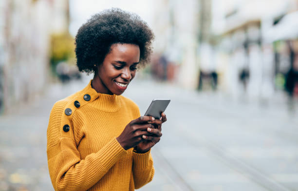 istock Young woman using smart phone in the city. 1203810546