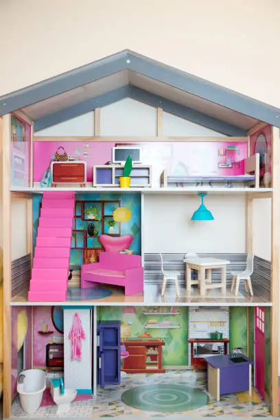 A Child's doll house with furniture on a yellow background - Image