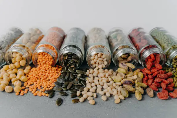 Image of nutrient pinenuts, mung beans, sunflower seeds, chickpea, pistachio spilled from glass containers. Healthy nutrition concept. Zero waste, food packaging