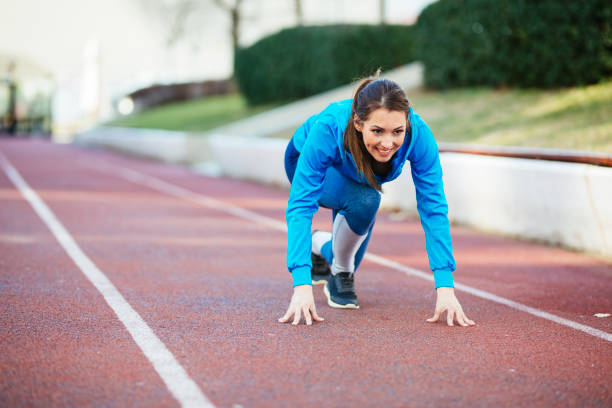 屋外で走るためのスタートポジションの女性アスリート - running track women running spring ストックフォトと画像