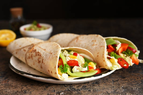 istock Mexican tortilla with beef, corn and vegetables with guacamole sauce on a concrete background. 1203814945