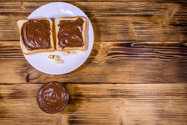 Two sandwiches with chocolate spread on a white plate. Top view