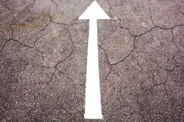 istock white arrow sign on the dry soil, ground, background 1203818894