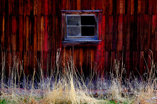 Old red barn in field late fall or autumn brown grass weathered wood