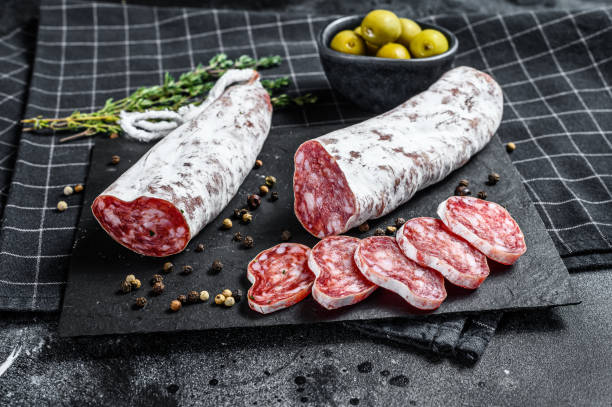 salame fuet tagliato a fette e rosmarino. salsiccia tradizionale spagnola. sfondo nero. vista dall'alto - dry cured ham foto e immagini stock