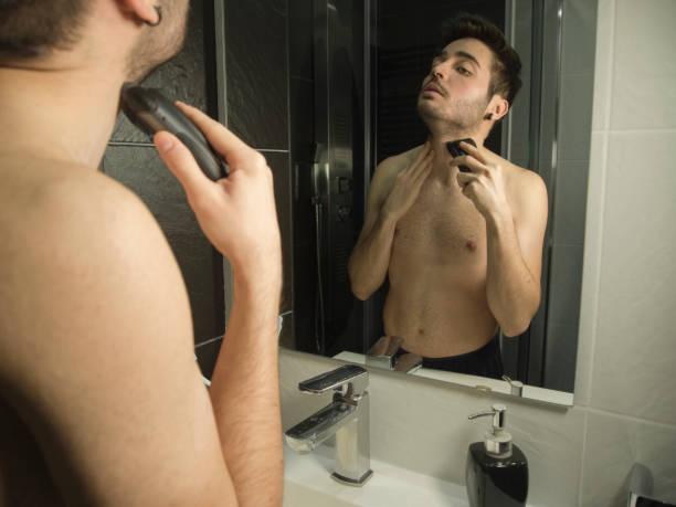 portrait of handsome caucasian man reflection in from of the mirror, shaving with a shaver - shaving men electric razor reflection imagens e fotografias de stock