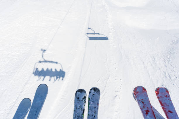 Personal perspective - siting on ski lift and looking down on skis and shadow of ski lift.