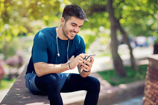 istock Young man is resting and texting in the park after run 1203821621