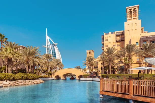 view of the chic seven star hotel burj al arab in the shape of a sail and the artificial canal with a bridge - madinat jumeirah hotel imagens e fotografias de stock