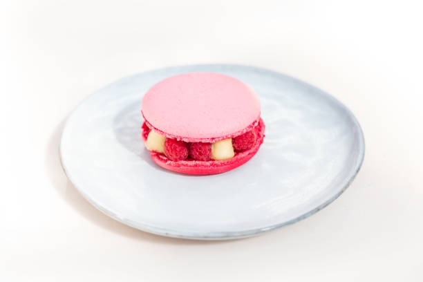 Pink macaroon with raspberry on a plate
