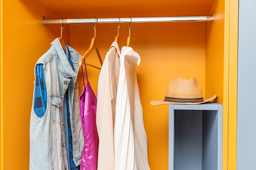 Bright wardrobe with casual men's and women's clothing in the room interior